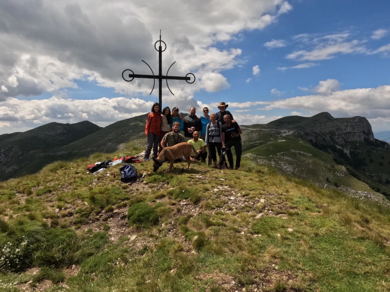 Eine Wandergruppe versammelt sich am Gipfelkreuz im Pangeon-Gebirge